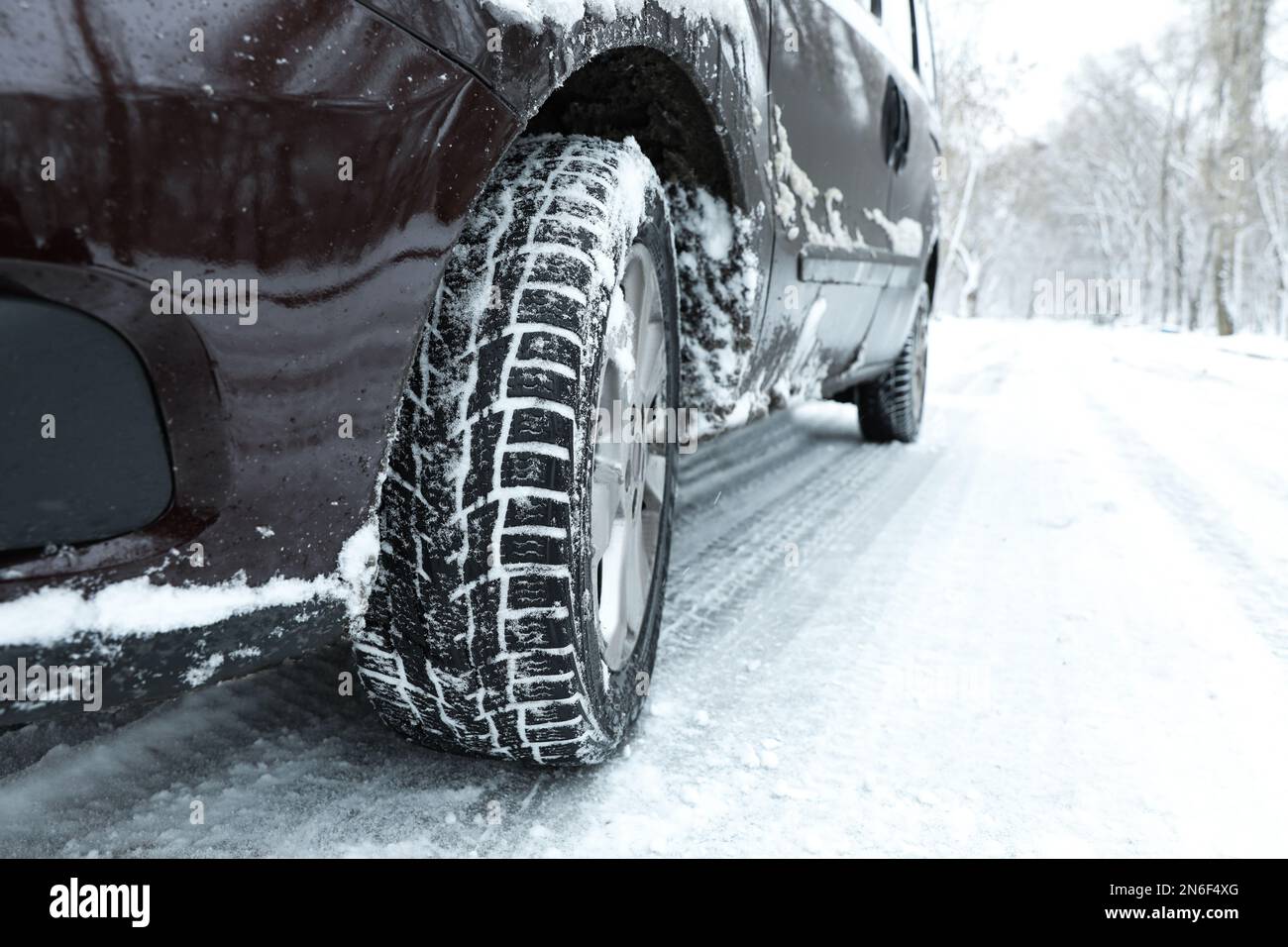 Auto moderna con pneumatici invernali su strada innevata, primo piano Foto Stock