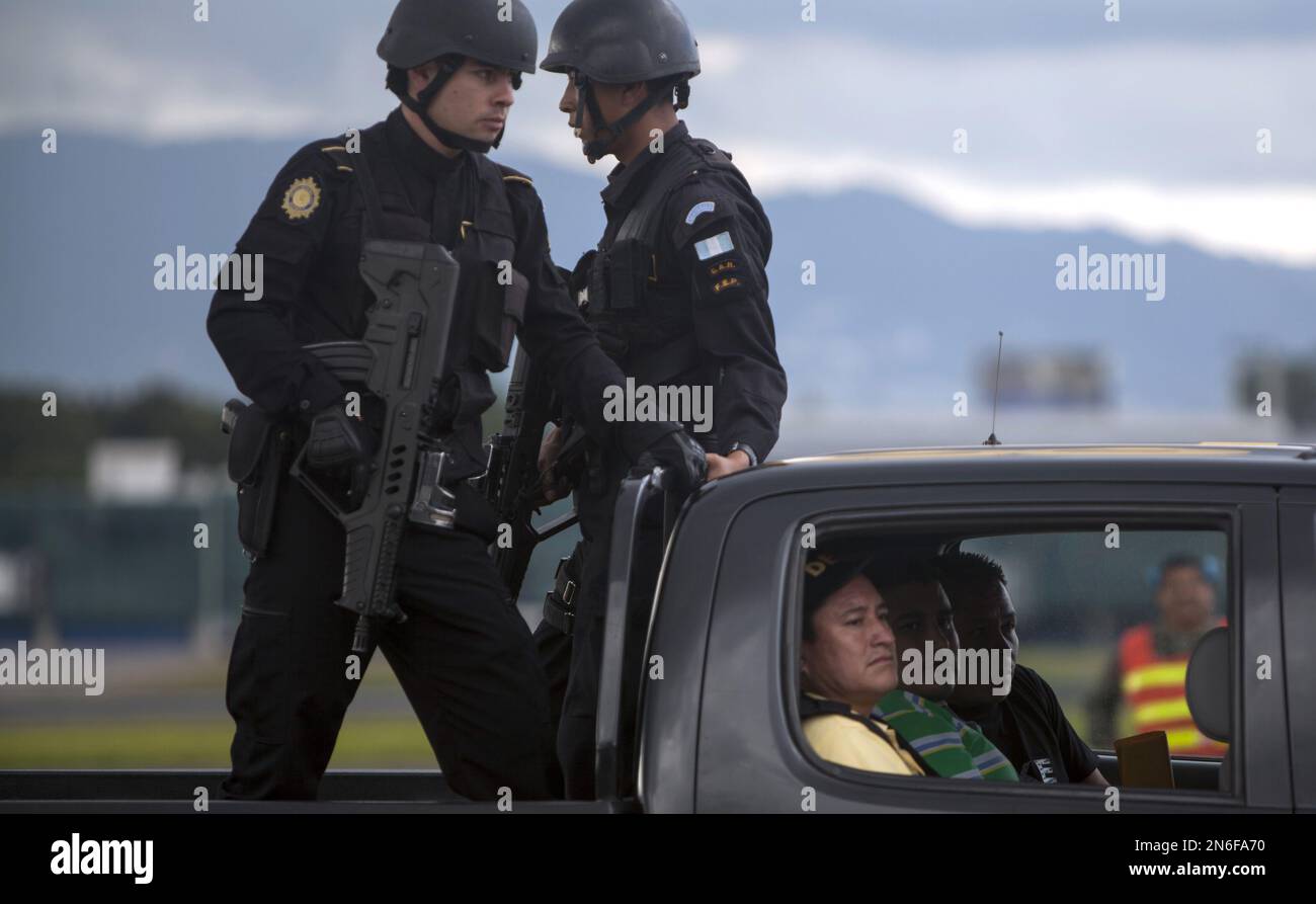 Police escort a man identified by Guatemala's government as Eduardo Francisco Villatoro Cano, alias "Guayo Cano," inside car second from left, as they leave an air force base in Guatemala City, Friday, Oct. 4, 2013. Guatemala's government says Villatoro Cano is a top leader of a local drug cartel that has connections with Mexico's Gulf Cartel, and that his cousin Edgar Waldini Herrera Villatoro was detained along with him in Tuxtla Gutierrez, Chiapas, Mexico, early Friday. (AP Photo/Luis Soto) Foto Stock
