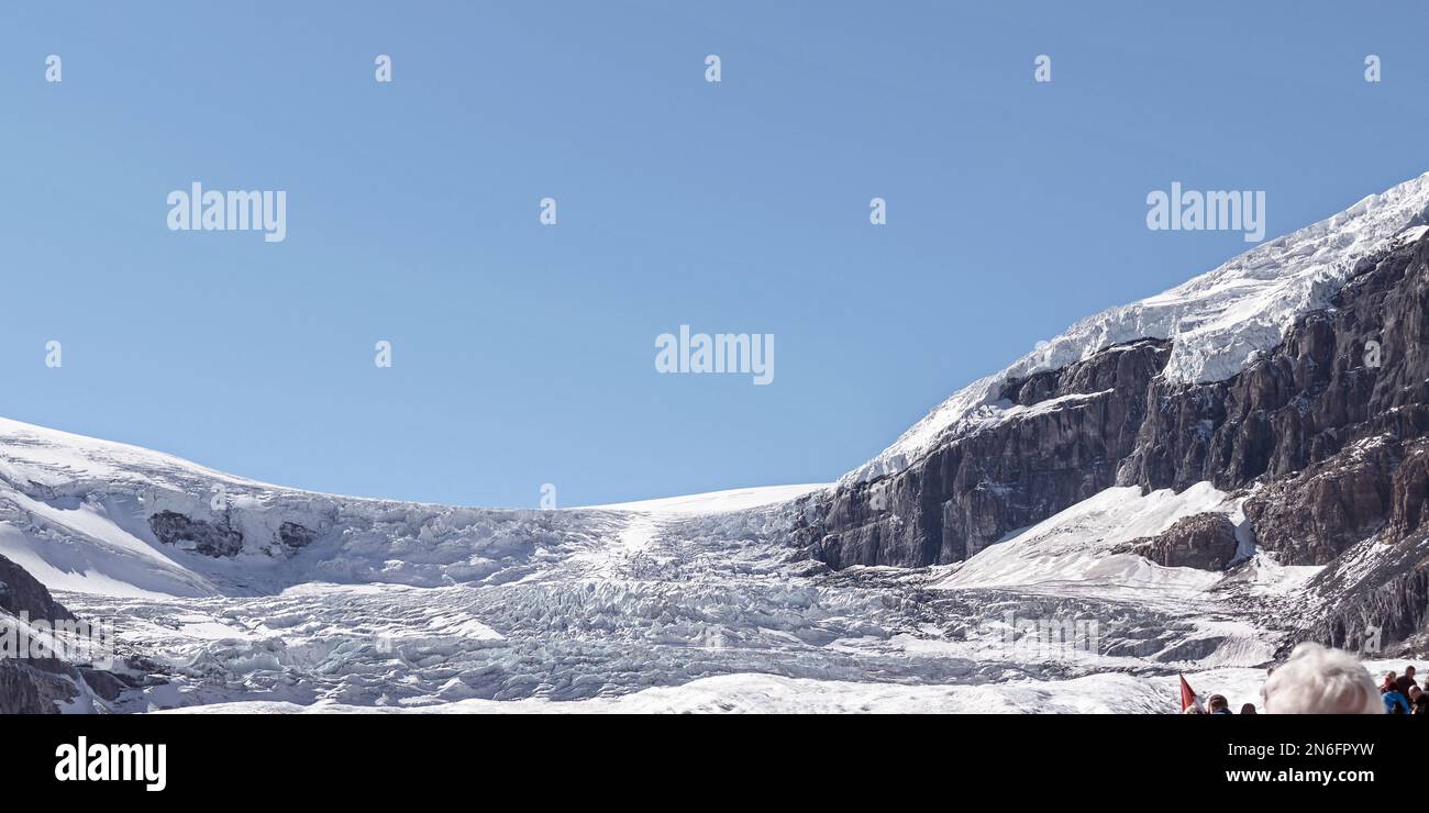 Primo piano del Ghiacciaio Peyto con un cielo blu cristallino sullo sfondo che mostra le teste dei turisti nell'angolo in basso a destra Foto Stock