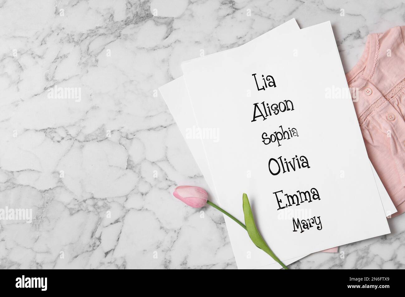 Elenco dei nomi dei bambini, dei fiori di tulipano e dei vestiti del  bambino su fondo bianco del marmo, disposizione piatta. Spazio per il testo  Foto stock - Alamy
