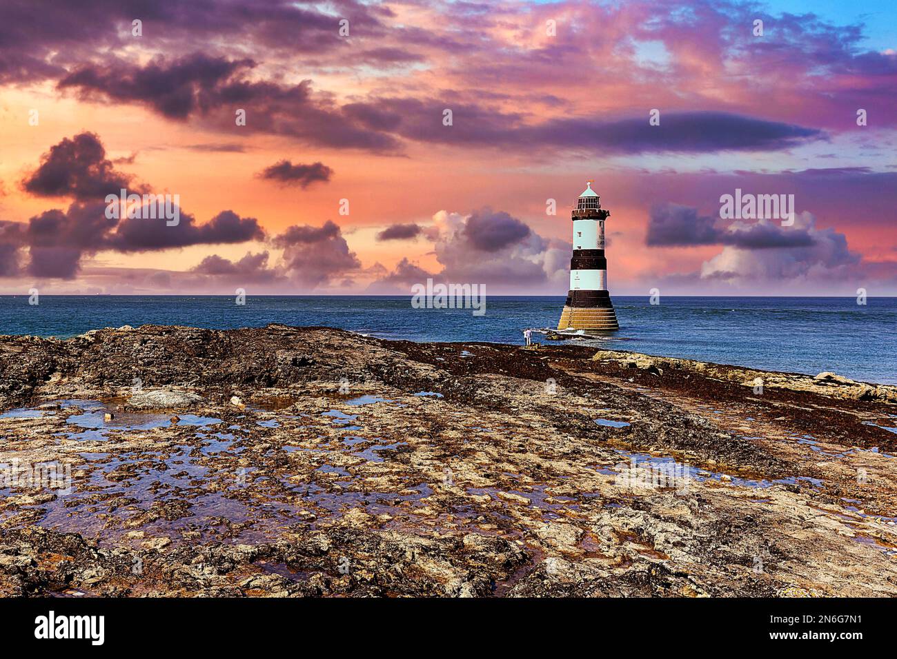 Trwyn Du Lighthouse sulla costa rocciosa, Penmon Lighthouse, cielo serale, Black Point, Isola di Anglesey, Galles, Regno Unito Foto Stock