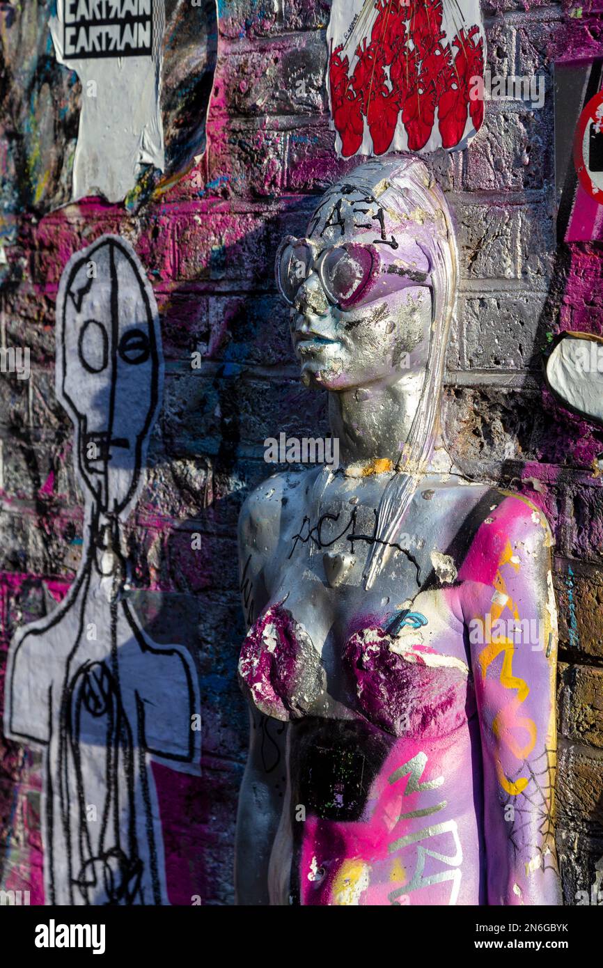 Vandalised 'Adam and Evaa' scultura di persona che esce da un muro di Urban Solid, Brick Lane, East London, UK Foto Stock
