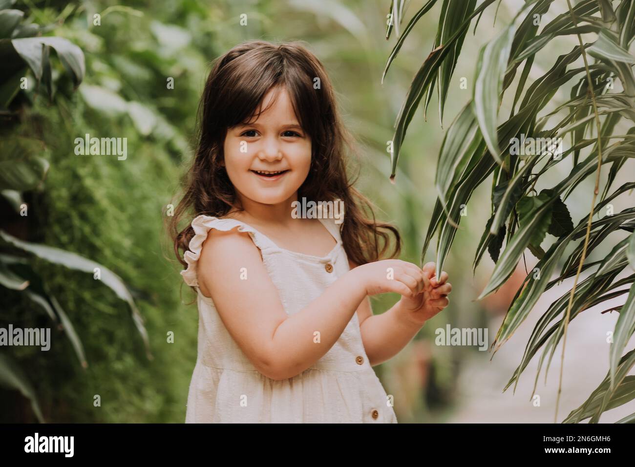 una bambina cammina nel giardino botanico. felice bambino e palme Foto Stock