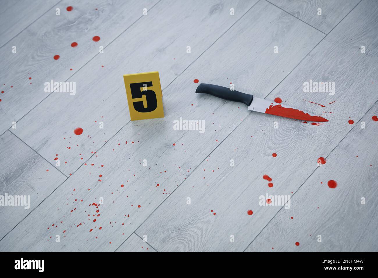 Coltello nel sangue vicino al marcatore della scena del crimine sul pavimento di legno Foto Stock