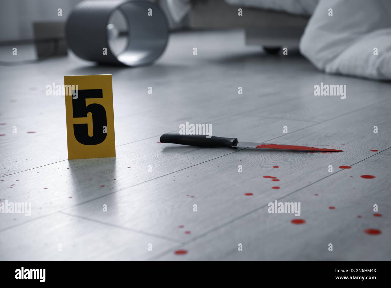 Coltello nel sangue vicino al marcatore scena del crimine su pavimento di legno all'interno Foto Stock