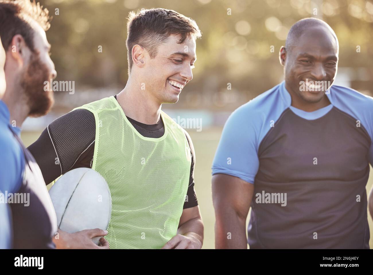 Gruppo di giocatori di rugby diversi in piedi in una huddle durante l'allenamento dopo una partita di pratica all'aperto su un campo. Lavorando sul loro piano di gioco per il Foto Stock