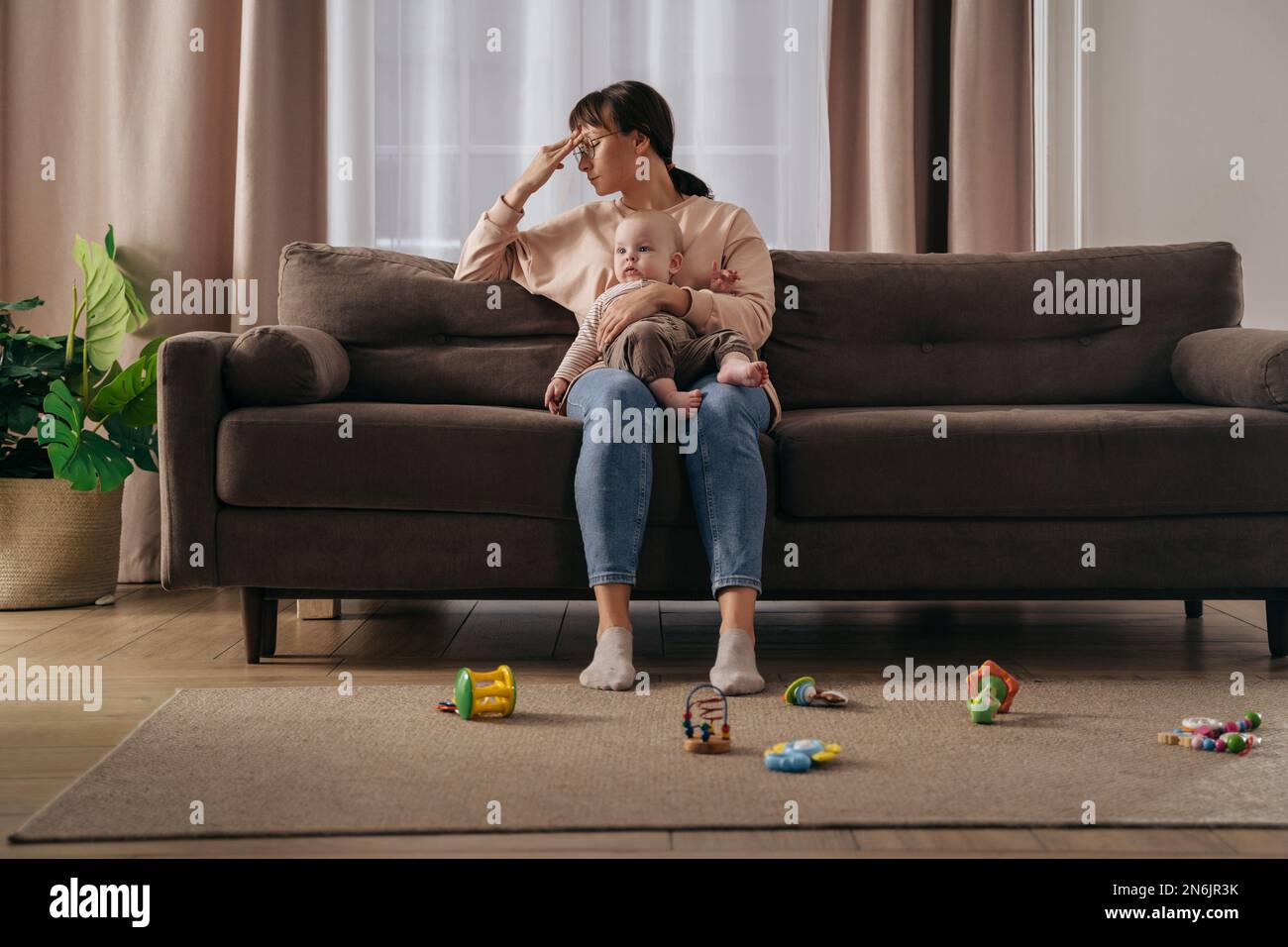 Madre single stanca che soffre di depressione postpartum. Donna frustrato esausta che tiene il suo bambino del toddler sulle ginocchia, sensibilità sollecitata con le notti insonni e le difficoltà stressanti di maternità Foto Stock