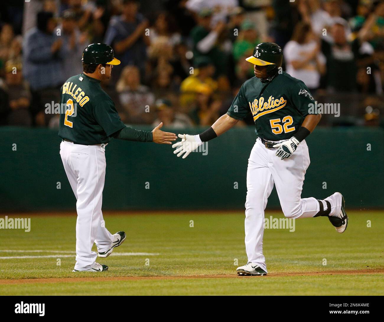 Oakland Athletics' Yoenis Cespedes (52) is congratulated by third base coach MIke Gallego (2) after hitting a home run during the second inning of a baseball game against the Minnesota Twins, Friday, Sept. 20, 2013, in Oakland, Calif. (AP Photo/Beck Diefenbach) Foto Stock