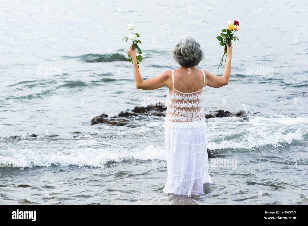 Salvador, Bahia, Brasile - 02 febbraio 2017: Una donna che ammira Candomble getta fiori in mare in onore di Iemanja il giorno della sua festa. Salvador, Foto Stock
