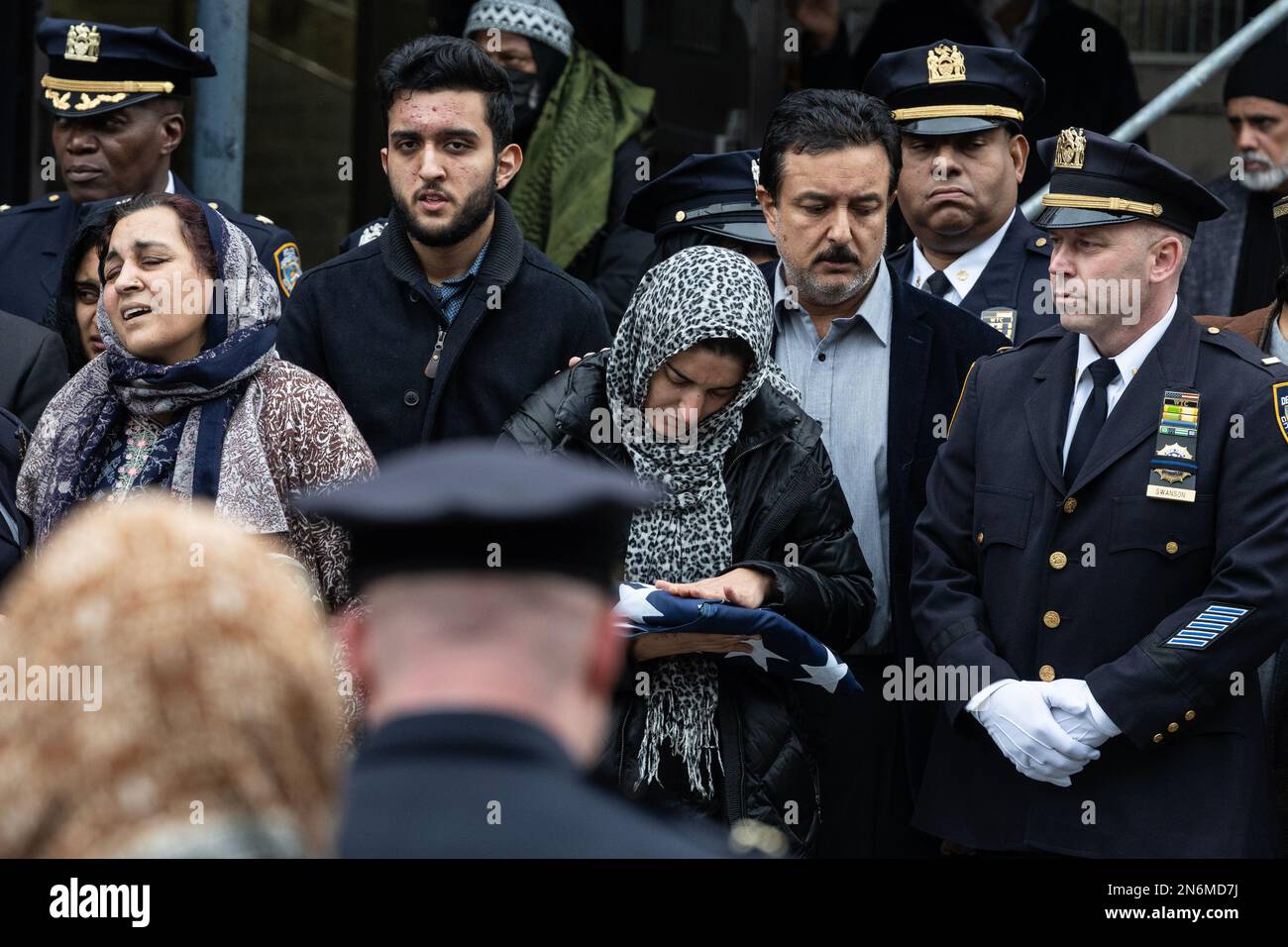LA moglie DI PO Adeed Fayaz tiene la bandiera ripiegata di NYPD ai suoi funerali al Makki Masjid Muslim Community Center di Brooklyn, New York, il 9 febbraio 2023 Foto Stock