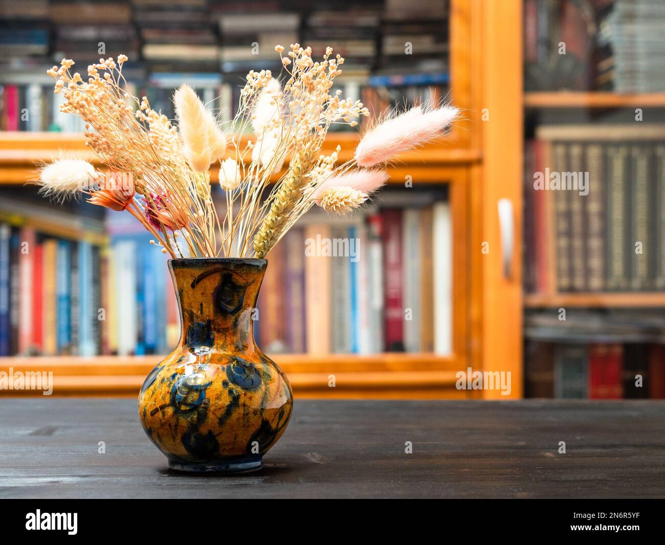 vista laterale del bouquet di piante essiccate in vaso su tavolo di legno marrone scuro con scaffale sullo sfondo Foto Stock