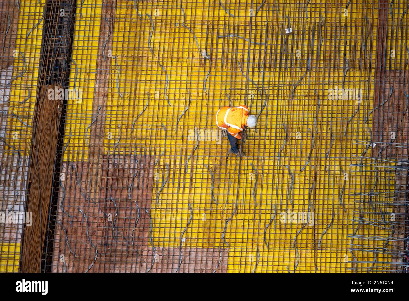 Vista dall'alto dei lavoratori che preparano una piastra di fondazione in cemento in un cantiere. Foto Stock