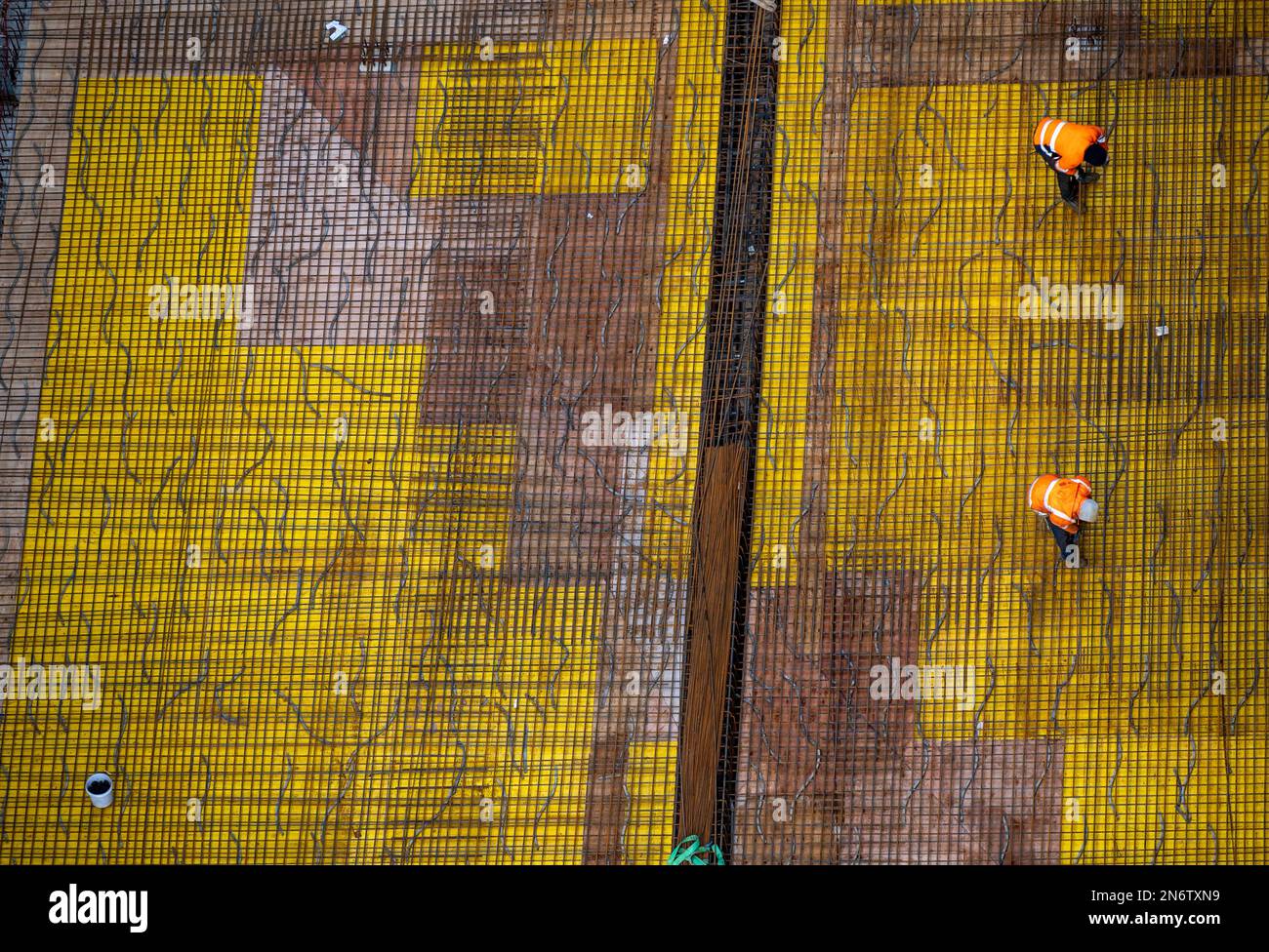 Vista dall'alto dei lavoratori che preparano una piastra di fondazione in cemento in un cantiere. Foto Stock