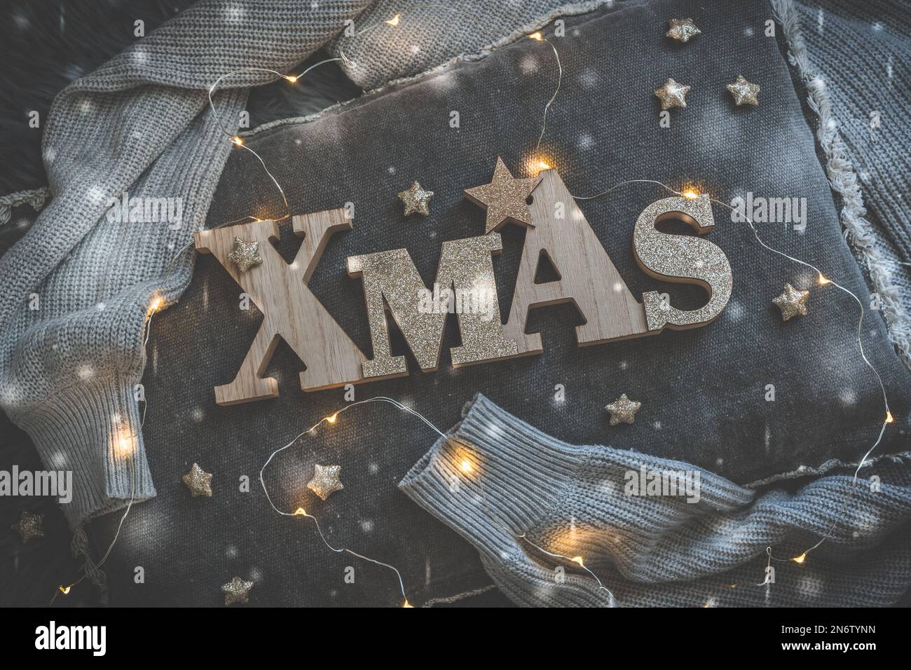 Parola natale in lettere maiuscole di legno, su un cuscino grigio con fata luci, vista dall'alto Foto Stock