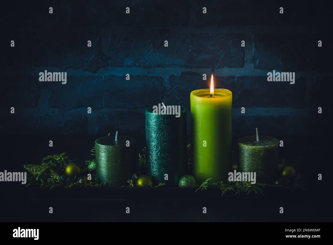 Corona dell'Avvento con quattro candele diverse in colori verdi su sfondo scuro, decorazione di natale, copia spazio Foto Stock