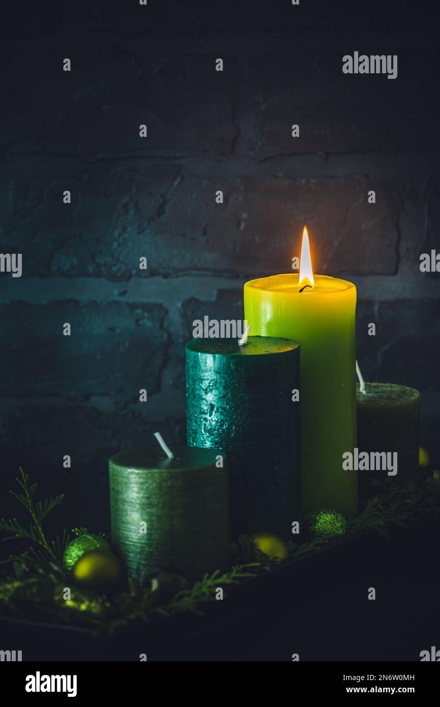 Corona d'Avvento con quattro candele diverse in colori verdi su sfondo scuro, decorazione di natale, verticale con spazio copia Foto Stock