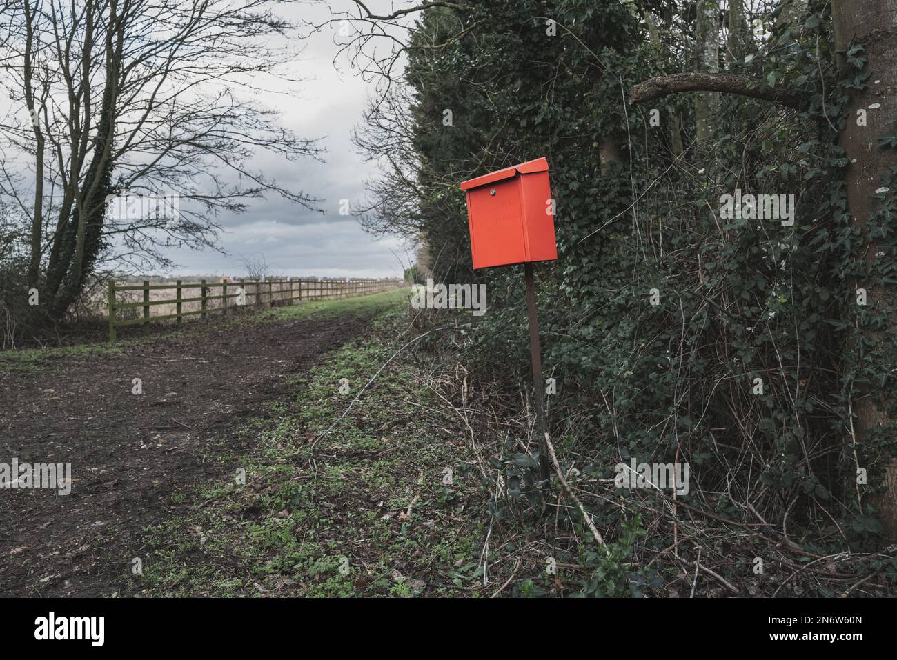 Casella di lettere rossa improvvisata vista all'esterno di un cottage rurale lungo una pista sterrata. Foto Stock