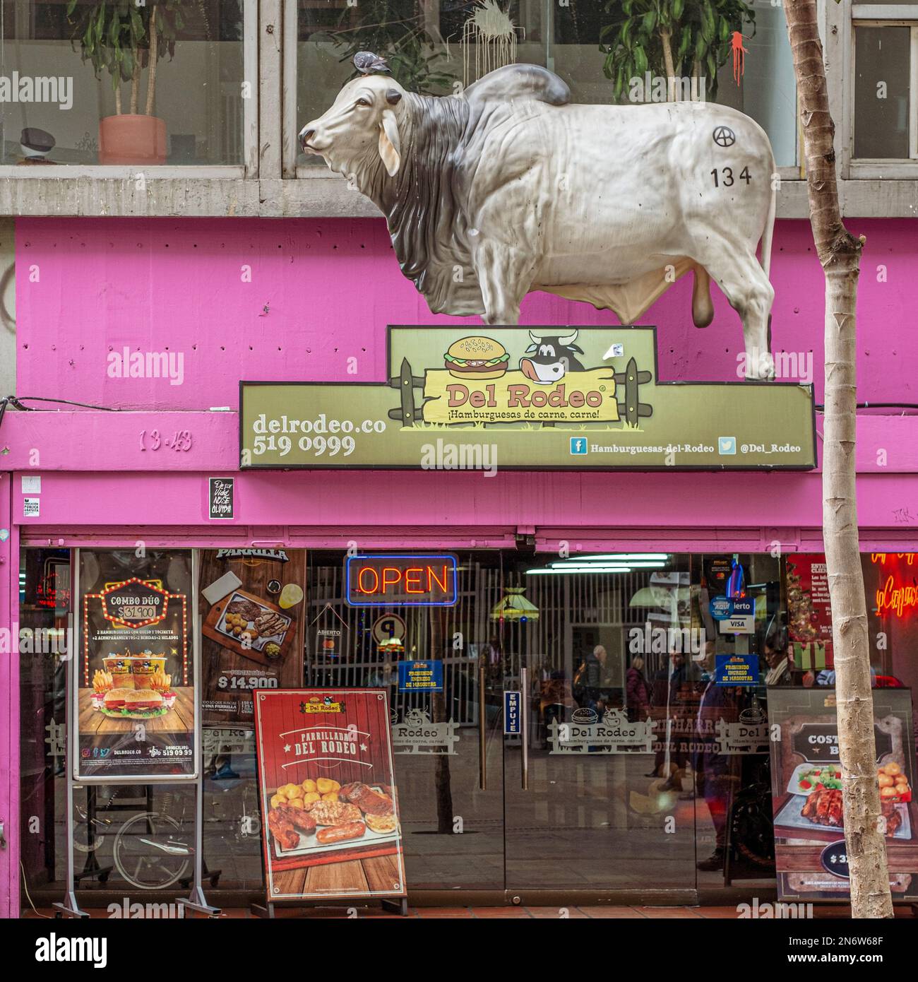 Un grande bue di plastica segna la finestra di un ristorante di hamburger e carne a Bogotà, Colombia Foto Stock
