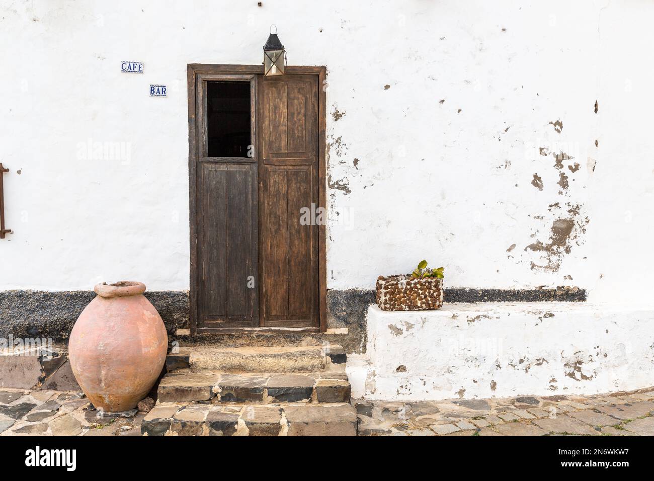 Porta d'ingresso di una casa a Betancuria, Fuerteventura, con vaso in terracotta, scatola di fiori e lanterna. Foto Stock