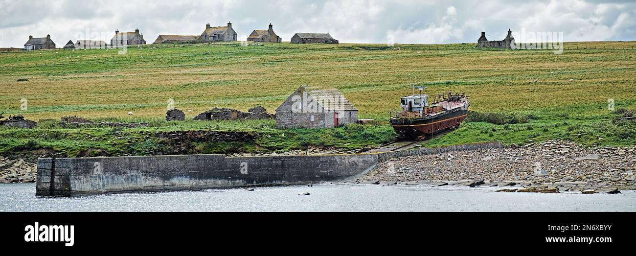Case di croft deserte sull'isola di stroma con una spiovente barca da pesca tirata su sullo scivolo del porto abbandonato Foto Stock