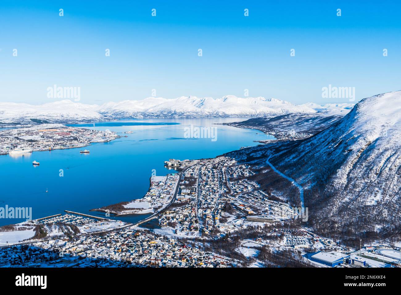 Vista incredibile della città di Tromso in Norvegia dalla cima di Storsteinen, una sporgenza di montagna di circa 420 m (1378 piedi) sopra il livello del mare, in una giornata invernale soleggiata, copia sp Foto Stock