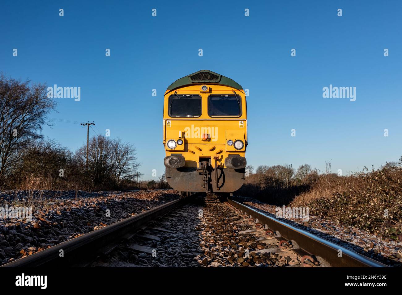 Un punto di vista frontale a basso angolo di un motore locomotivo per merci che si avvicina ad un trasgressatore su una linea ferroviaria in un'immagine di sicurezza industriale con copy spac Foto Stock