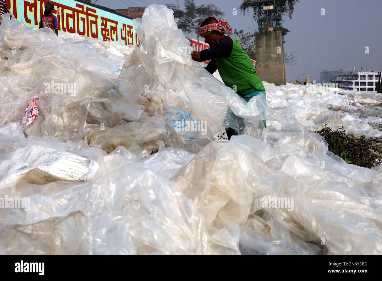 Dhaka, Dhaka, Bangladesh. 10th Feb, 2023. Le persone lavano il vecchio politene in acqua di fiume e lo asciugano al sole sulle rive del fiume Buriganga a Dhaka. Questi politene scartato sono raccolti da vari rifiuti. Poi lavati in acqua di fiume e fusi con calore per fare vari prodotti. Questi politeni sono altamente inquinanti e fatalmente dannosi per la biodiversità e per l'ambiente. Un'indagine ha trovato uno strato di 8-piedi di politene alla parte inferiore del fiume di Buriganga. (Credit Image: © Syed Mahabubul Kader/ZUMA Press Wire) SOLO PER USO EDITORIALE! Non per USO commerciale! Foto Stock