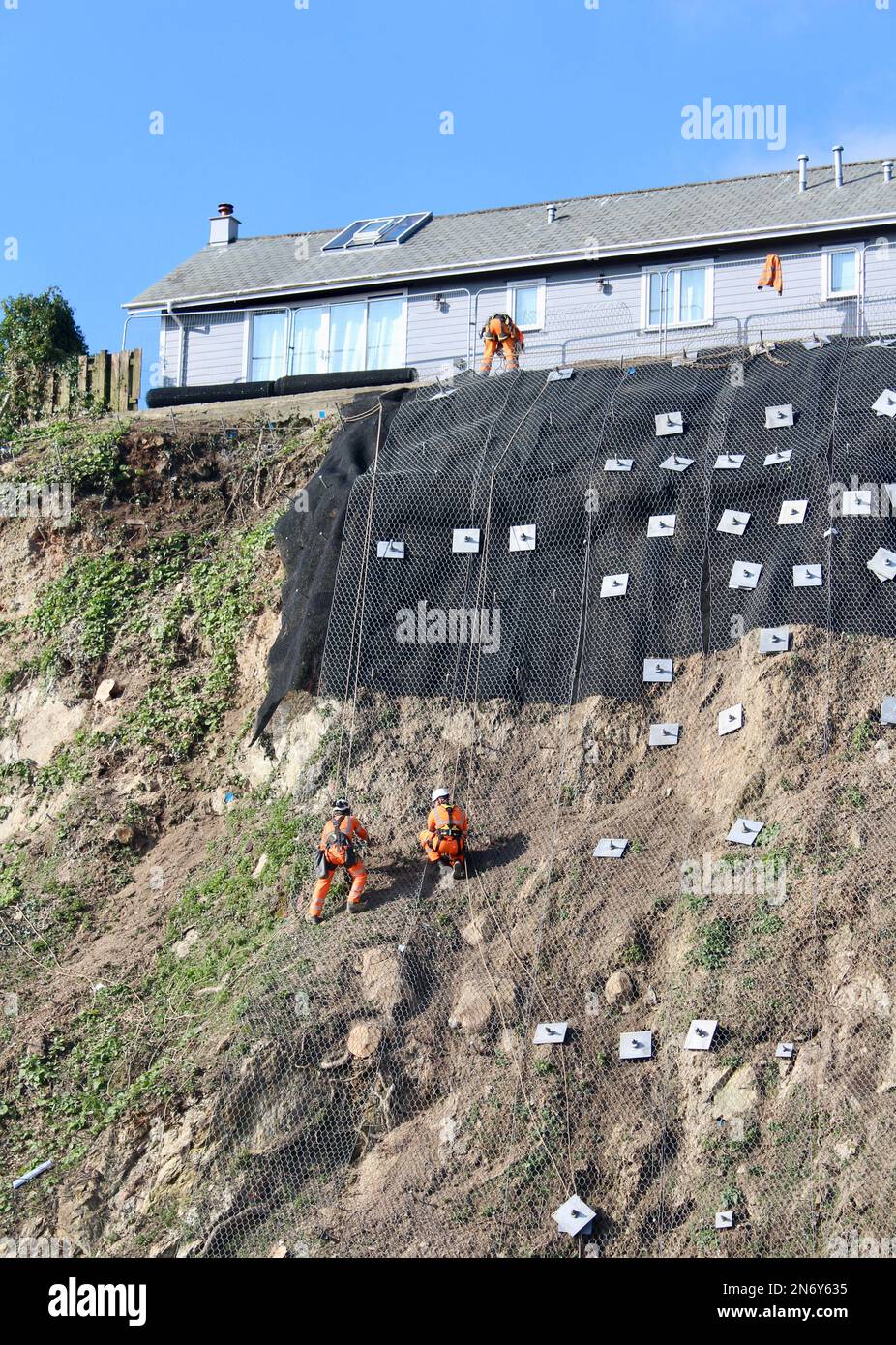Lavori di stabilizzazione della scogliera presso il parcheggio di Quarry Lane a Falmouth, Cornovaglia, Inghilterra. I lavoratori in discesa svolgono un lavoro essenziale. Foto Stock