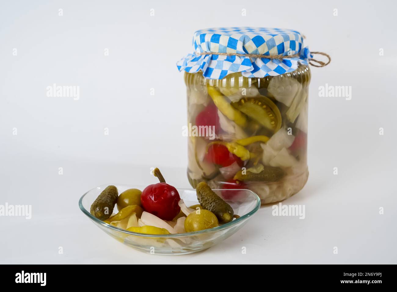 Cetrioli misti, crauti, pepe, pomodori e cetrioli in vaso di vetro e piatto isolato su fondo bianco. Foto Stock