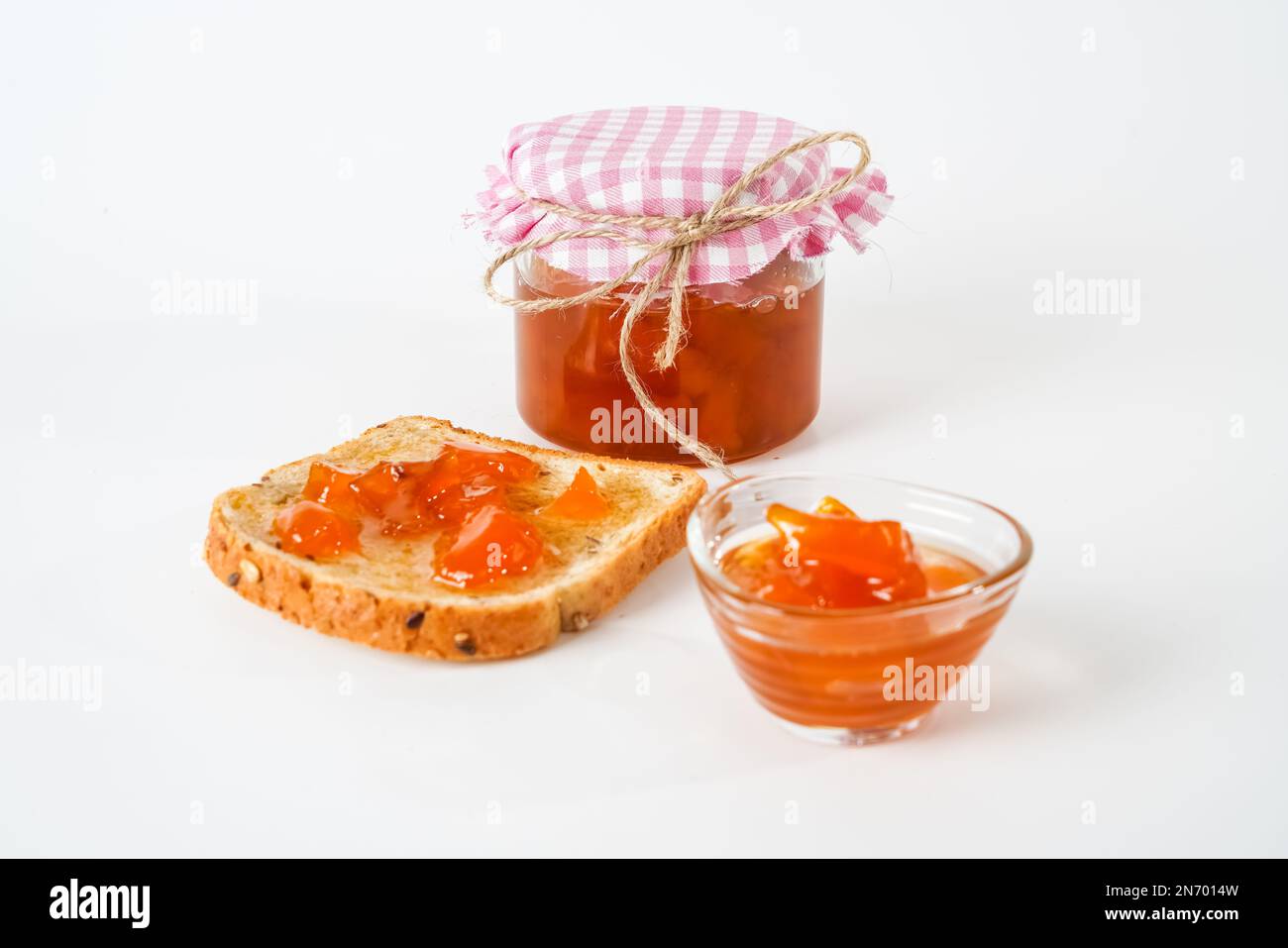 Marmellata di albicocche fatta in casa, vasetto, ciotola e una fetta di pane con marmellata isolata su fondo bianco. Foto Stock