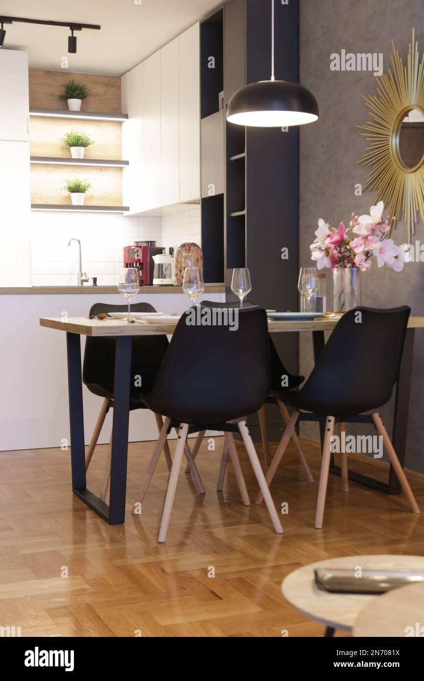 Tavolo da pranzo in cucina con piatti, utensili e grande vaso con bouquet di fiori Foto Stock