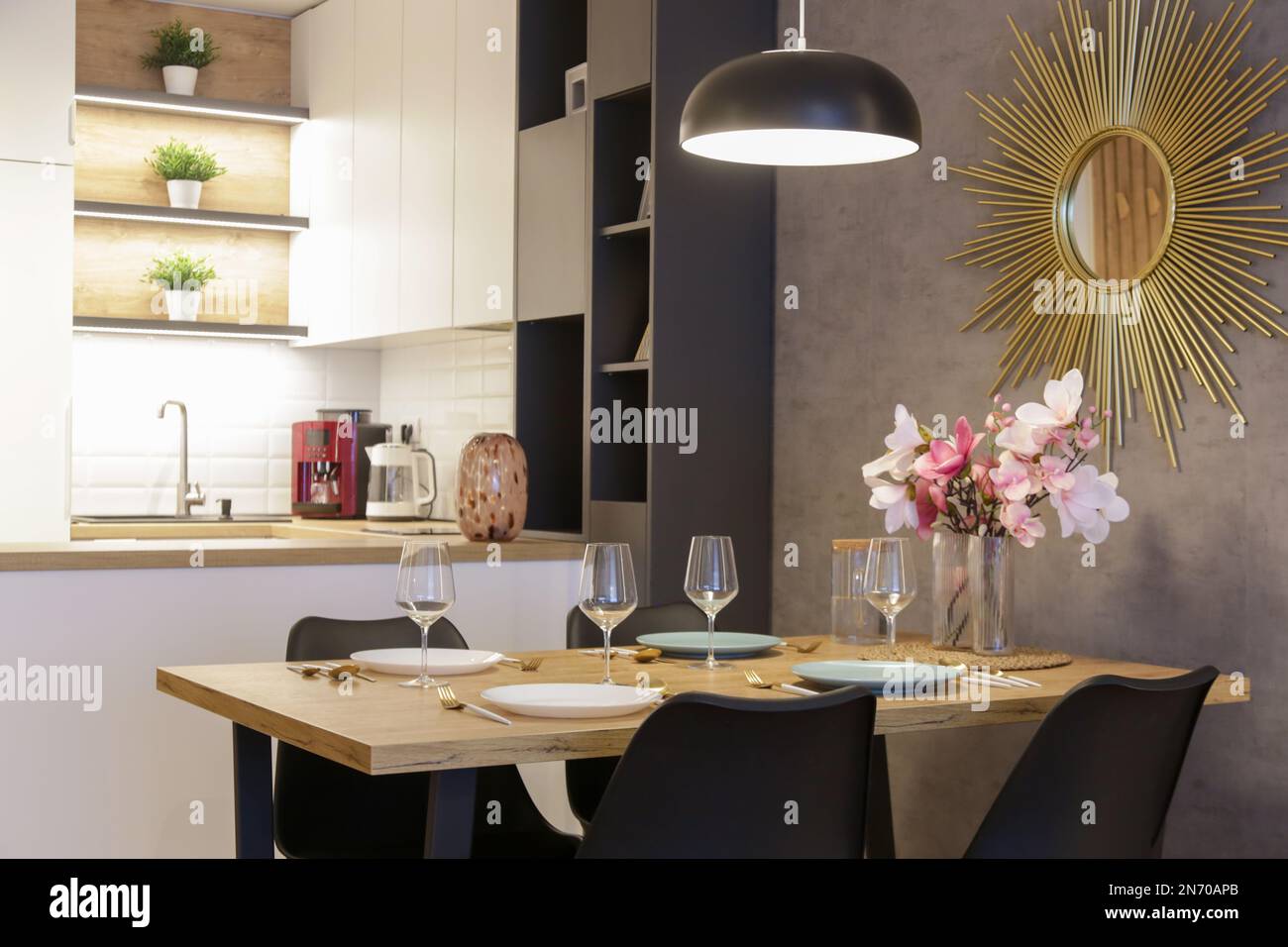 Tavolo da pranzo in cucina con piatti, utensili e grande vaso con bouquet di fiori Foto Stock