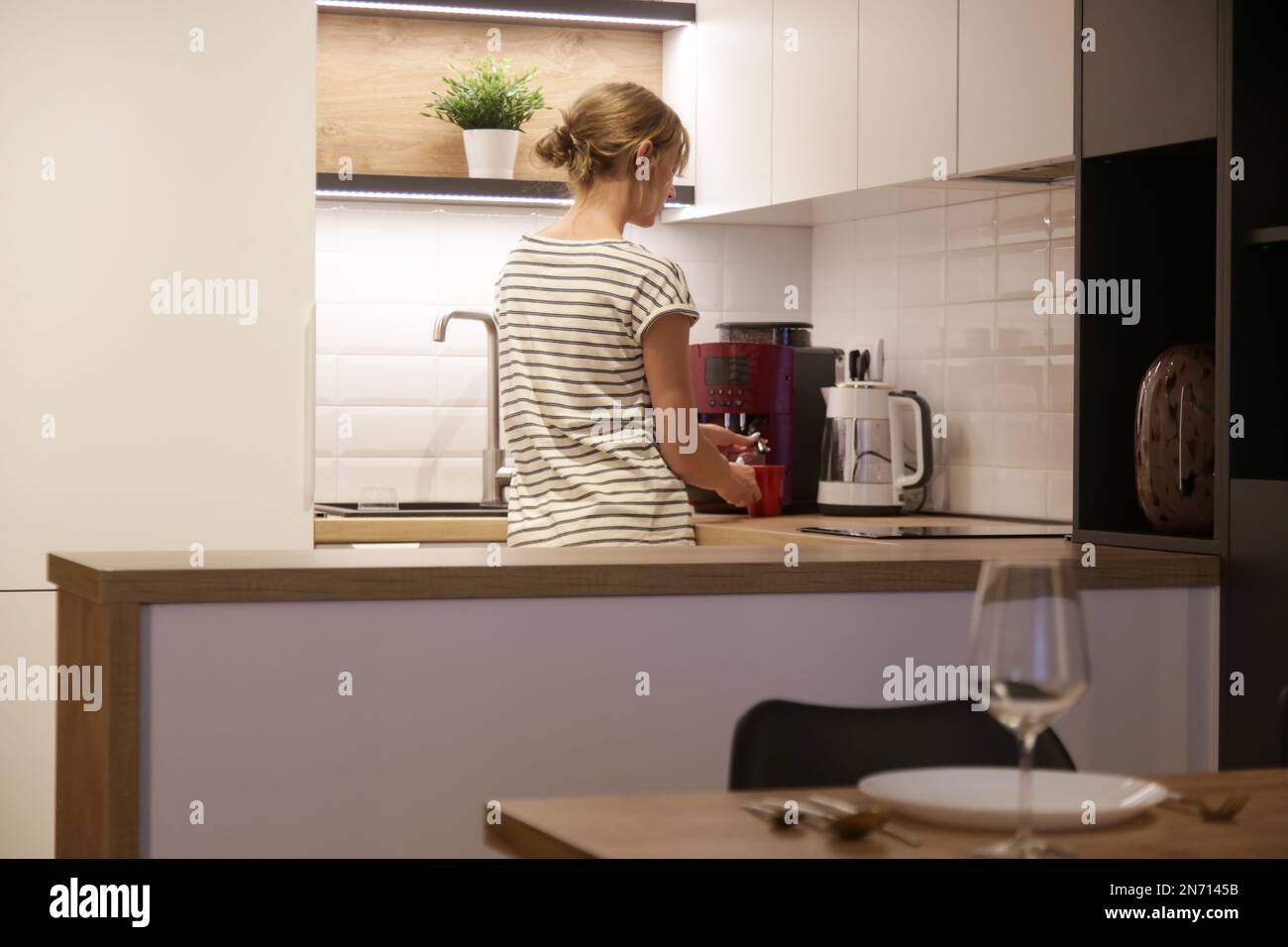 Donna che prepara un espresso fresco in una macchina per il caffè. Donna che prepara una grossa tazza di caffè a casa. Foto Stock
