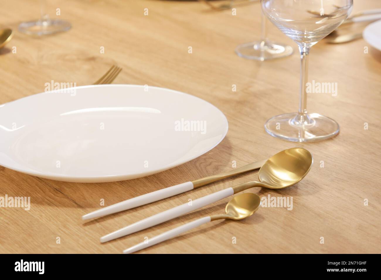 Tavolo da pranzo con piatti in ceramica bianca, set di posate in argento con manici bianchi e bicchieri da vino Foto Stock