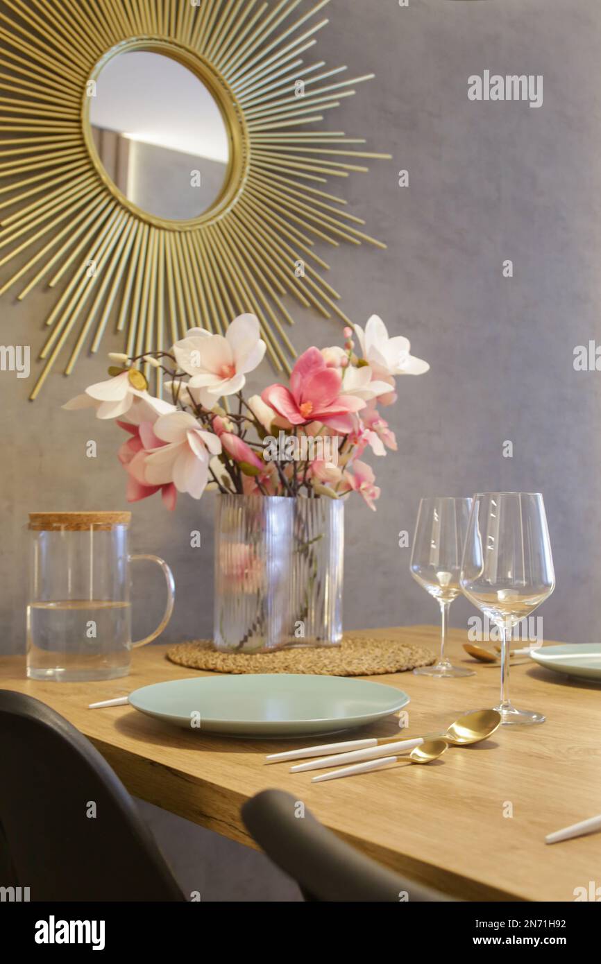Tavolo da pranzo in cucina con piatti, utensili e grande vaso con bouquet di fiori Foto Stock