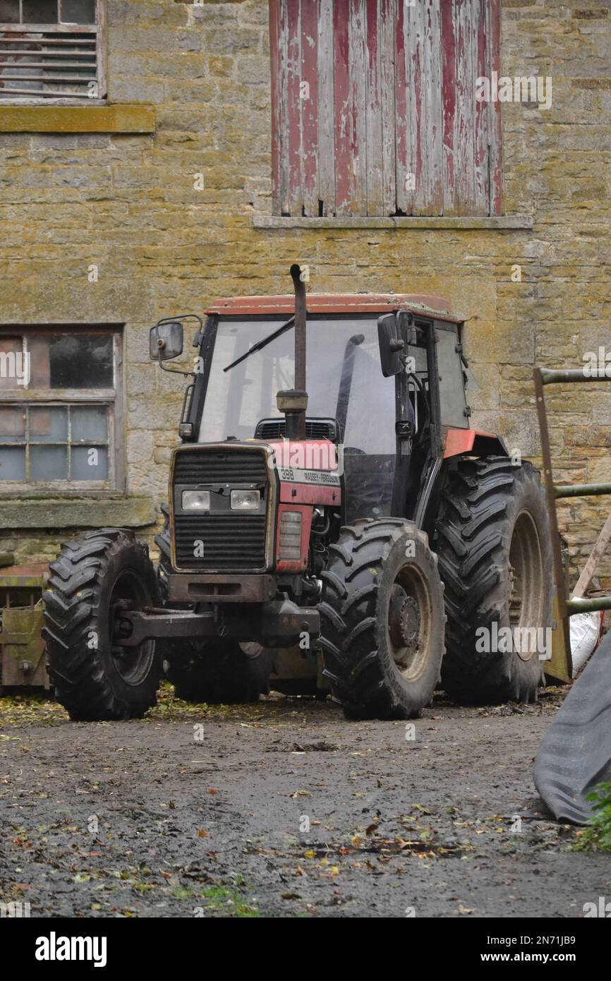 Trattore in Un cortile agricolo - trattore Massey Ferguson - macchine agricole con pneumatici piccoli e grandi - Northumberland - Regno Unito Foto Stock