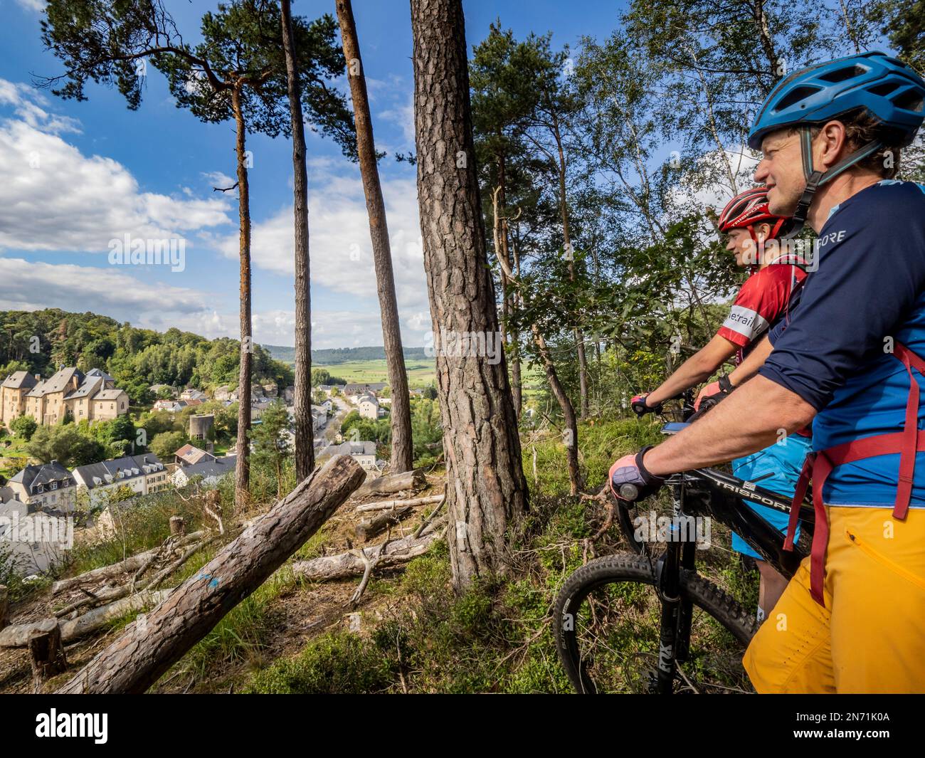 E-mountain biker su un unico sentiero nella foresta vicino a Burginster. Blicjk sul villaggio e castello di Burginster, Château de Bourglinster (lato est) a Burglinster, Lussemburgo. Il castello risale al 1231, di proprietà dello Stato di Lussemburgo dal 1968. È uno degli oltre 100 castelli e châteaux del Lussemburgo. Foto Stock