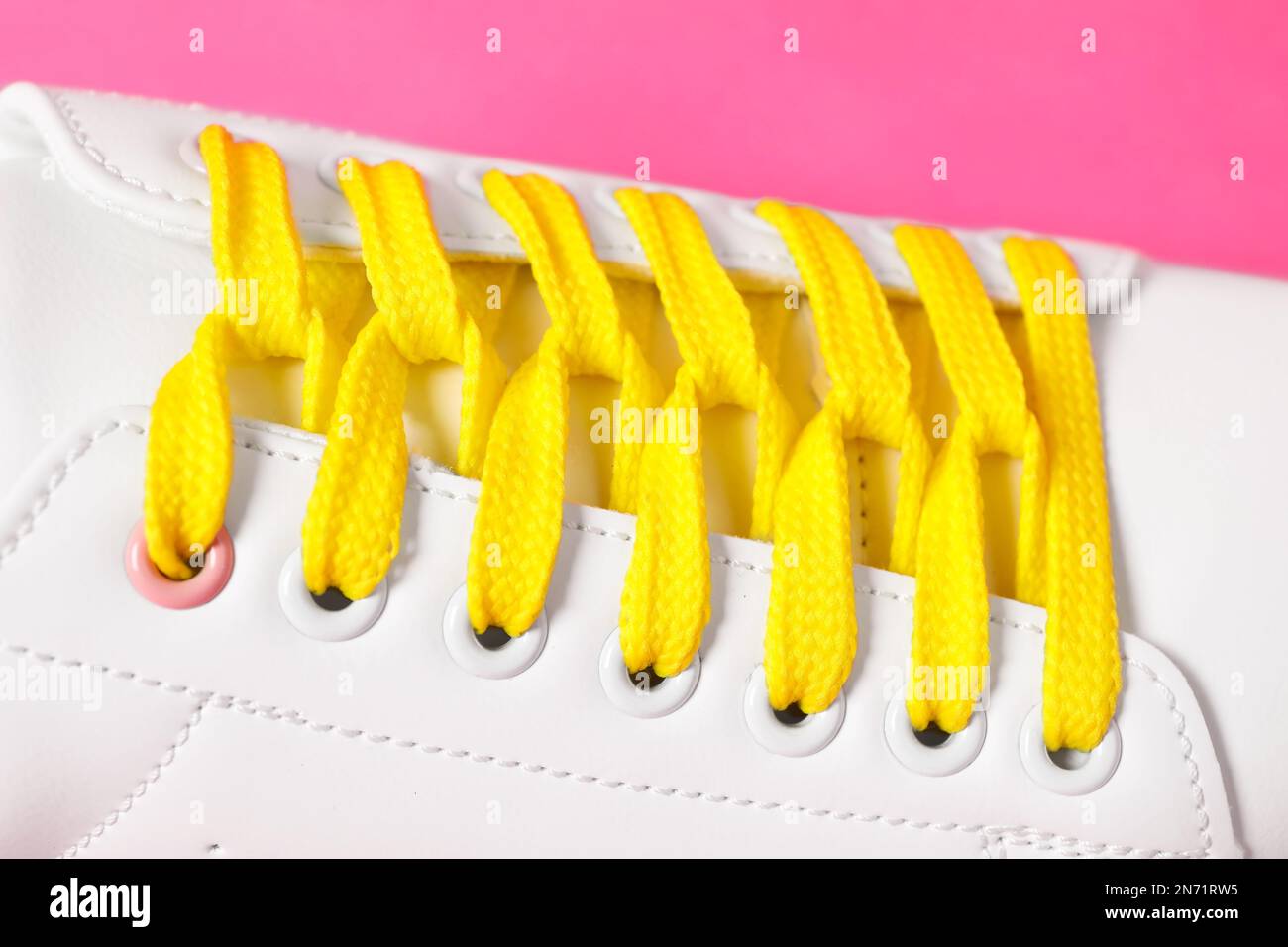 Scarpa elegante con lacci gialli su sfondo rosa, primo piano Foto Stock