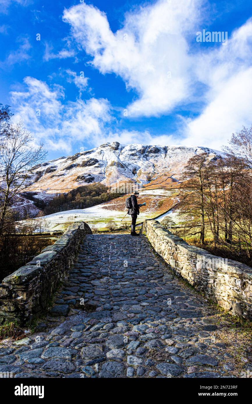 Un camminatore in piedi su New Bridge a Borrowdale studiando la sua mappa con Dale Head sullo sfondo. Foto Stock