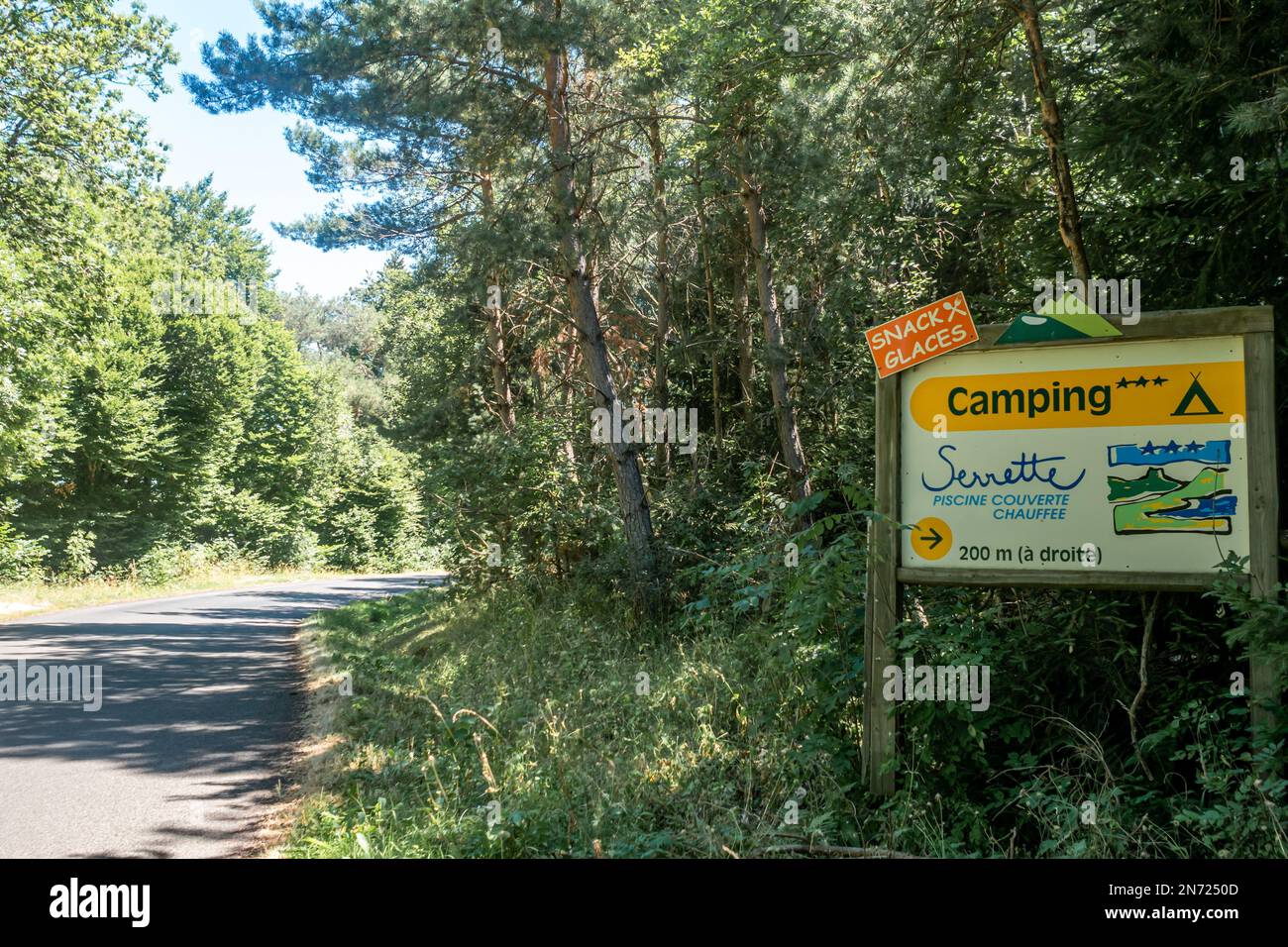 Una strada vuota con un cartello pubblicitario di Camping de Serrette, Chambon sur lac, Francia Foto Stock