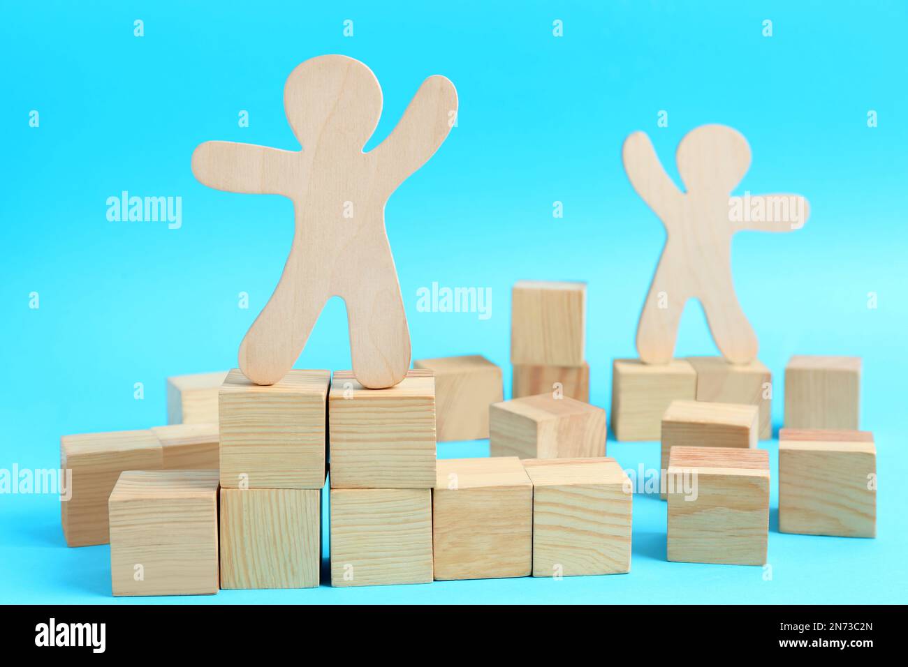 Cubi di legno e figure umane su sfondo azzurro. Concetto di ruoli sociali Foto Stock