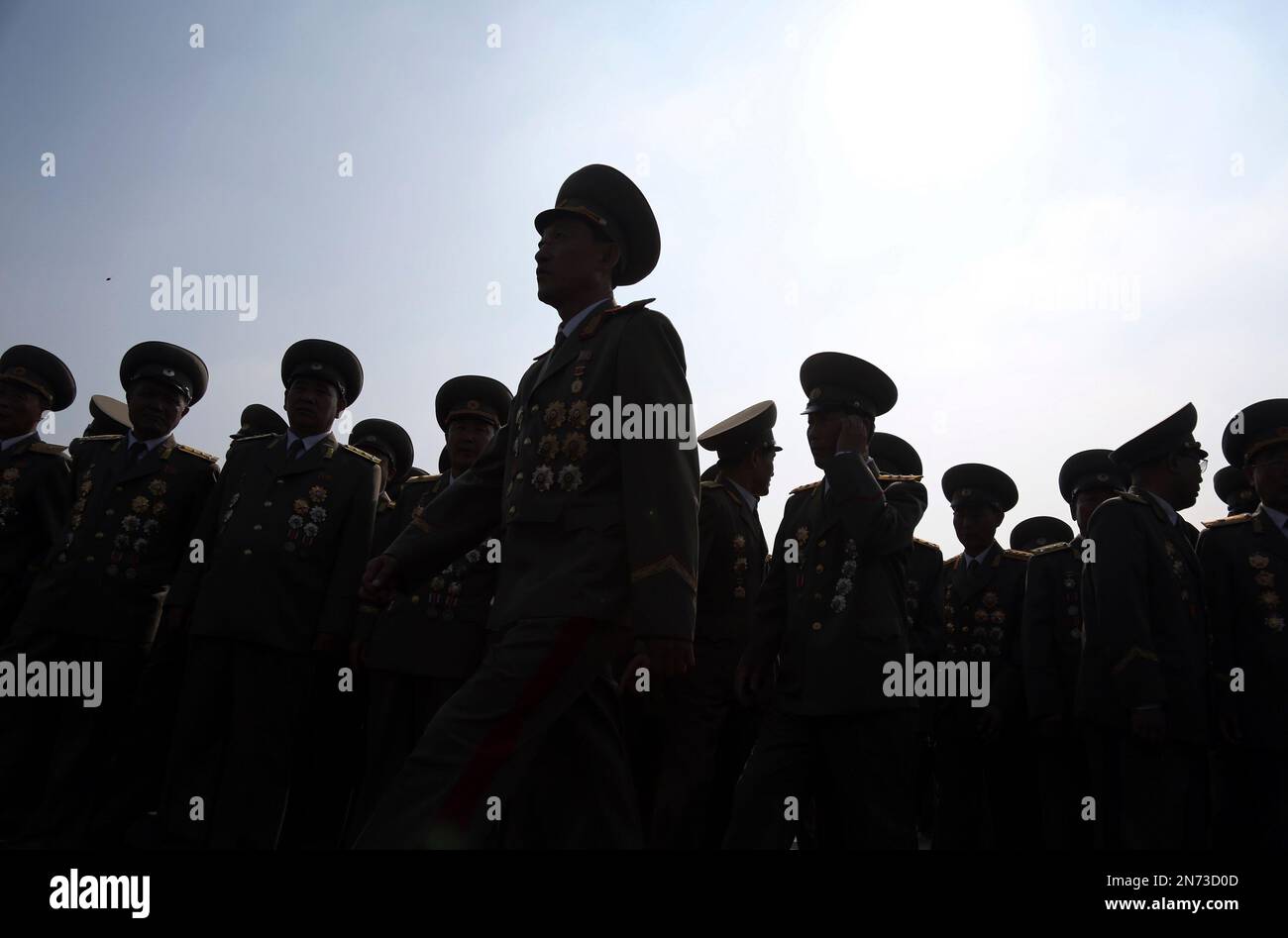 North Korean military officers are silhouetted as they gather at the cemeteries of fallen fighters of the Korean People's Army (KPA) on Thursday, July 25, 2013 in Pyongyang, North Korea as part of ceremonies marking the 60th anniversary of the signing of the armistice that ended hostilities on the Korean peninsula. (AP Photo/Wong Maye-E) Foto Stock