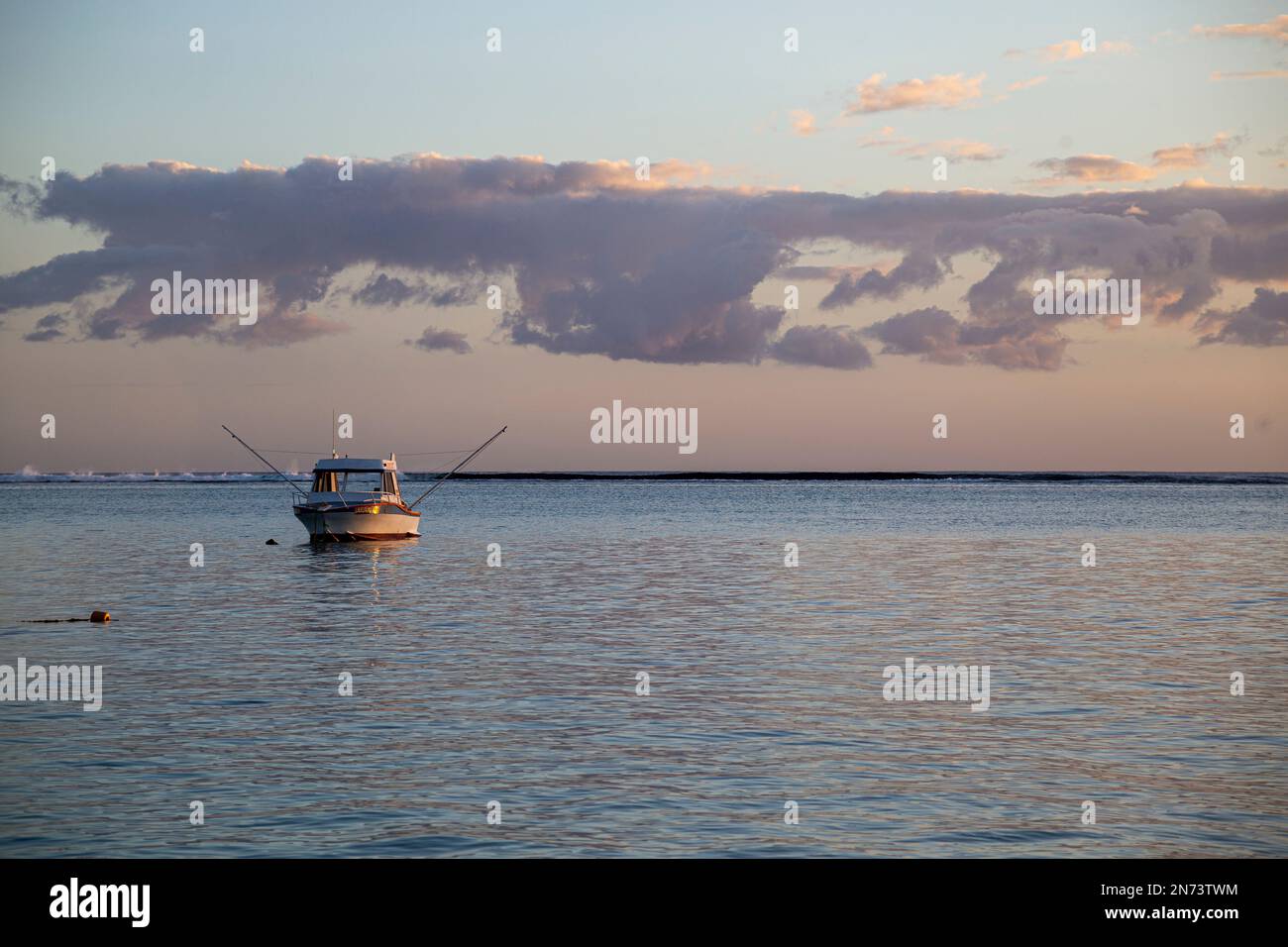 Vista del tramonto dalla spiaggia di flic en Flac nell'isola di Mauritius, Africa fino all'oceano con una sola barca Foto Stock