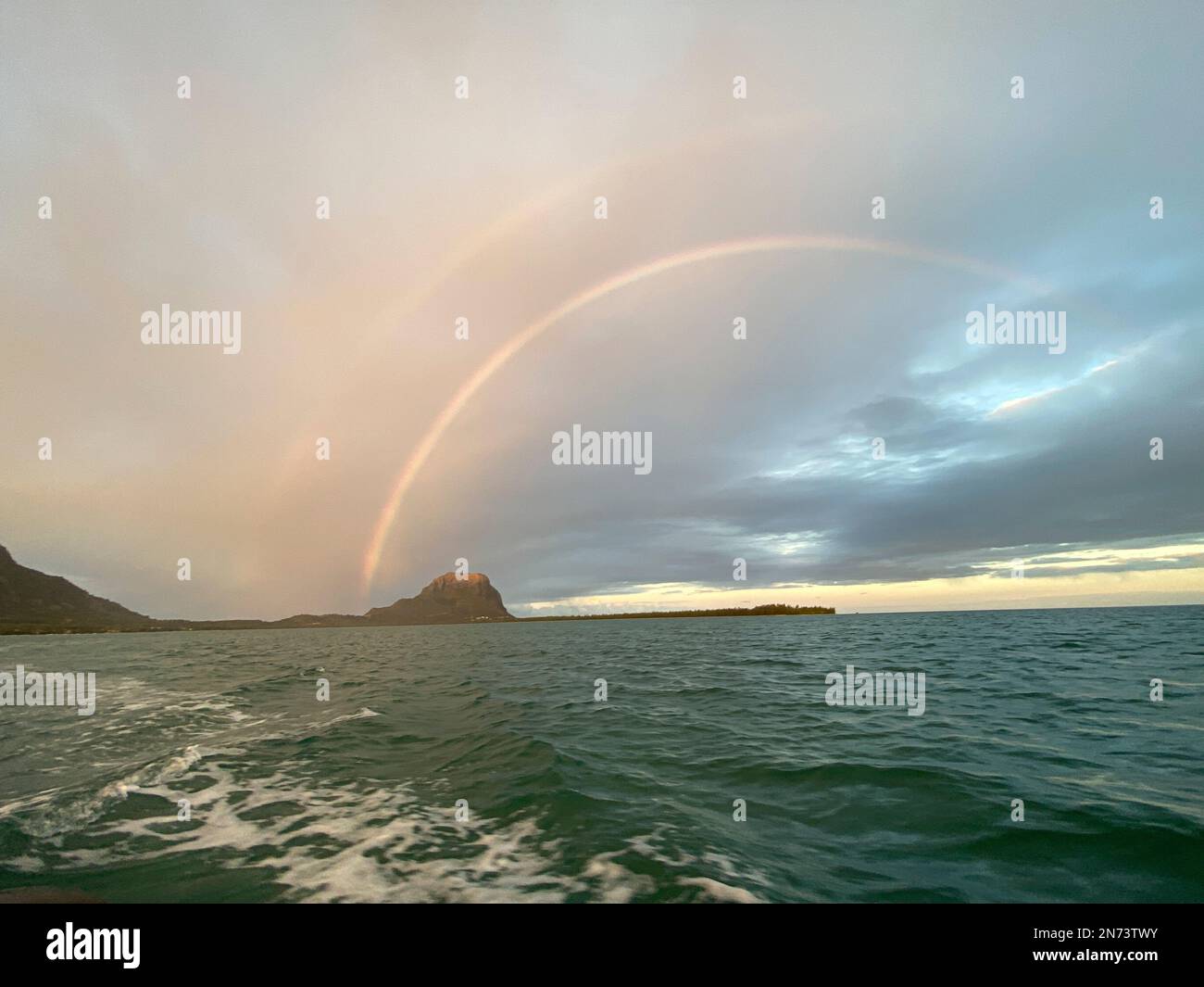Un arcobaleno che parte vicino al monte le Morne con laguna, oceano e spiaggia a Mauritius. Foto Stock
