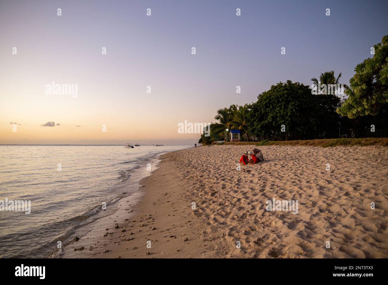 Vista dalla spiaggia di Flic en Flac con bambini che giocano sulla sabbia, Mauritius, Africa Foto Stock