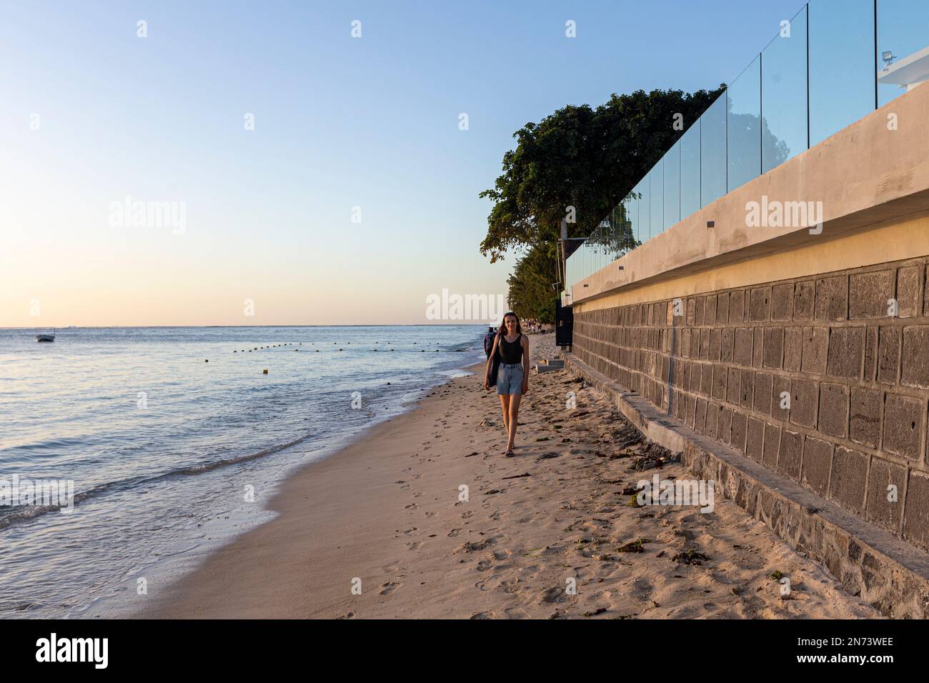 Una giovane donna che cammina lungo la spiaggia di flic en flac nell'isola di mauritius, africa Foto Stock