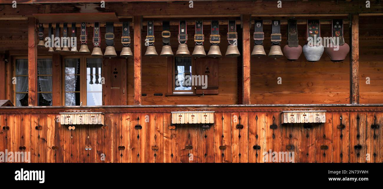 Campane di mucche di anni diversi appendono su un balcone in legno, Grindelwald, Canton Berna, Svizzera Foto Stock