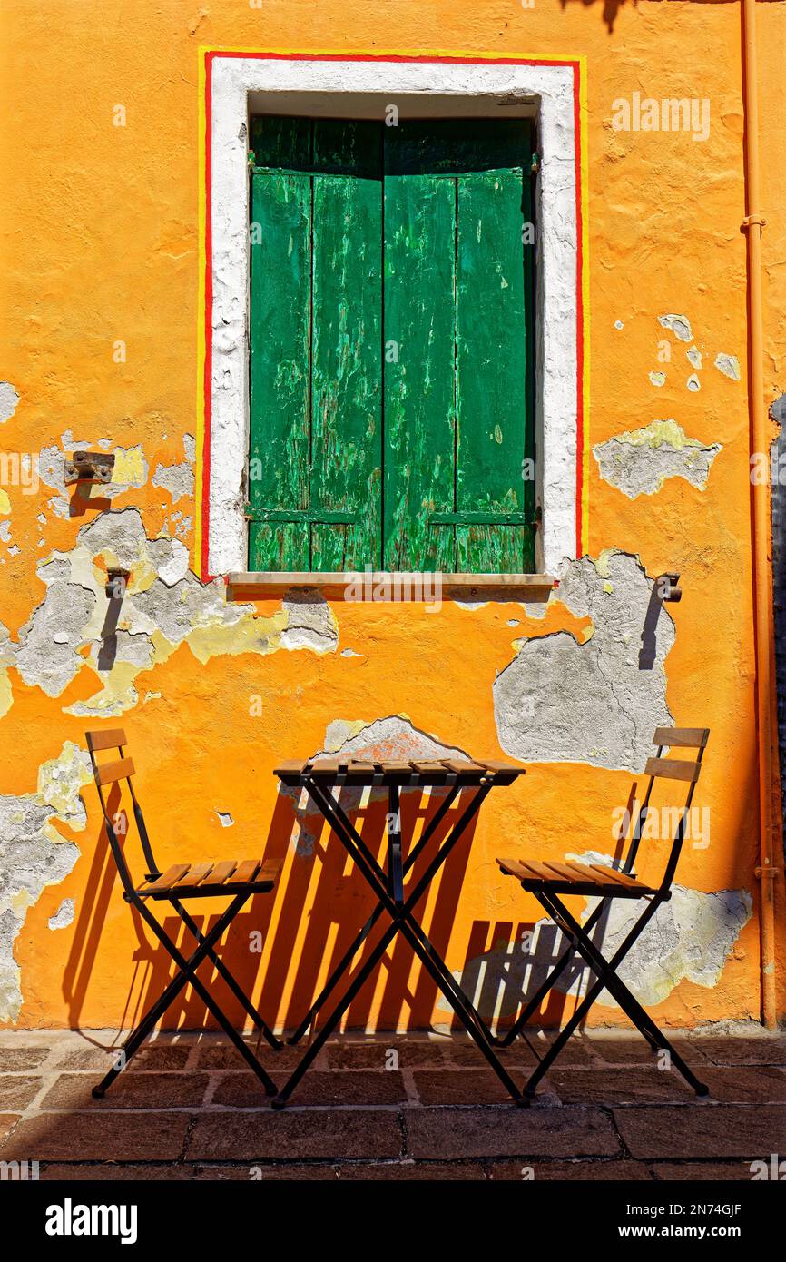 Due sedie in legno e un tavolo davanti ad una parete di casa con intonaco da peeling Foto Stock