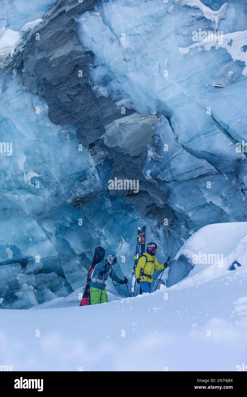 Due snowboarder professionisti e sciatori esplorano e sciano una grotta di ghiaccio sul ghiacciaio Pitztal, Pitztal, Tirolo, Austria Foto Stock