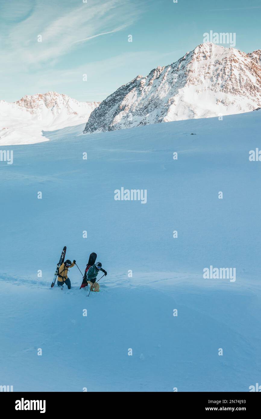 Due snowboarder professionisti e sciatori esplorano e sciano una grotta di ghiaccio sul ghiacciaio Pitztal, Pitztal, Tirolo, Austria Foto Stock